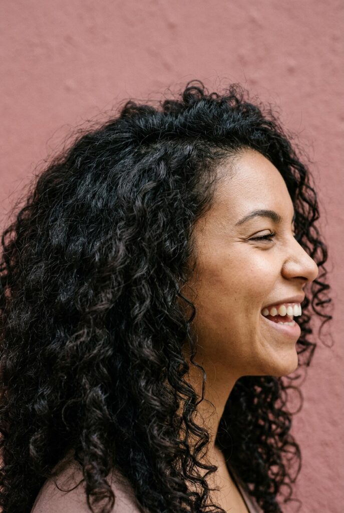 Woman with scrunched curls created by squeezing wet hair upward for defined, bouncy natural curls